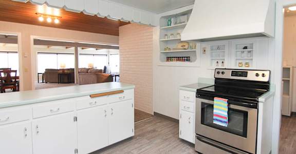 A modern kitchen with white cabinets and a stove top oven.