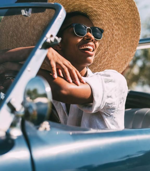 a man sitting in a convertible car with a hat