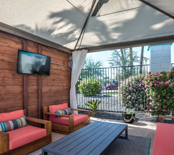 A patio with a TV, two chairs, and a table.
