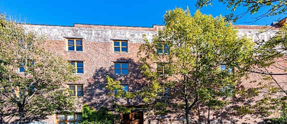 A red brick building with trees in front.
