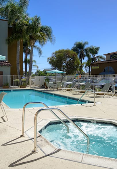 A large swimming pool surrounded by sun loungers and umbrellas.
