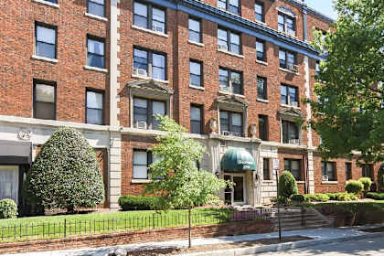 a large brick building with a green awning and a sidewalk