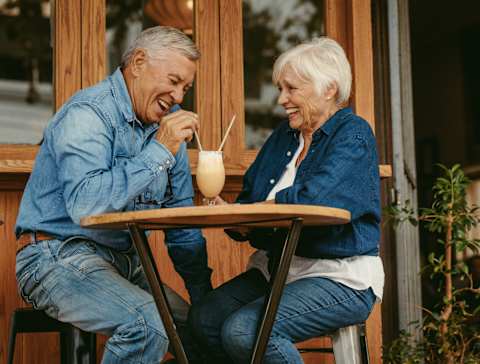 An older couple enjoying a drink together at a table.