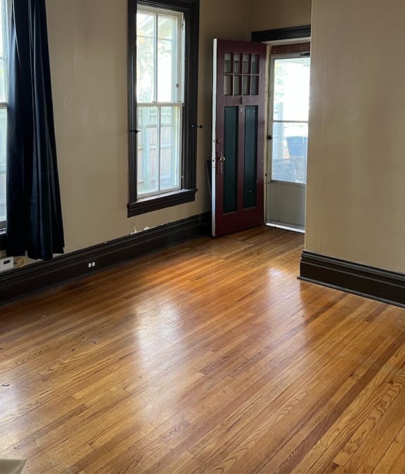 an empty room with a ceiling fan and two windows