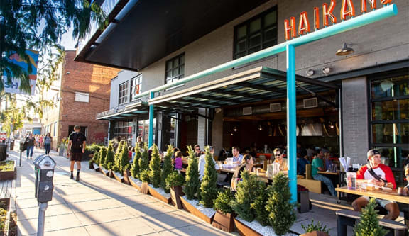 people sitting at tables outside of a restaurant