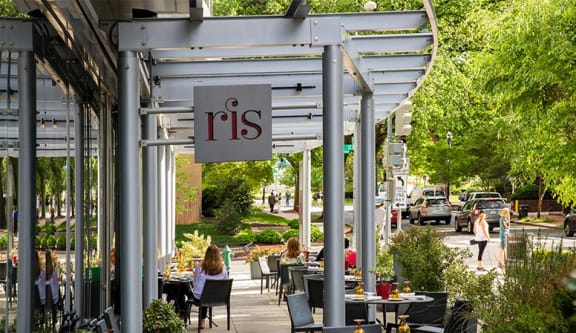 a restaurant patio with tables and chairs under awning