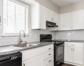 a kitchen with white cabinets and a wooden table at Hidden Woods, Decatur, GA
