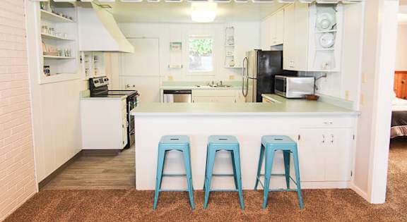 A kitchen with a white counter and blue stools.