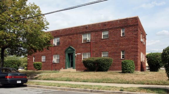 a red brick building with a green door and a black car parked in front of it