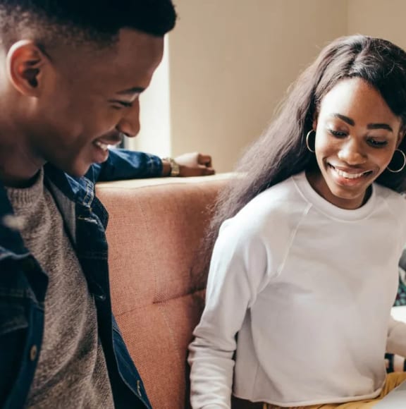 a man and a woman laughing while sitting on a couch