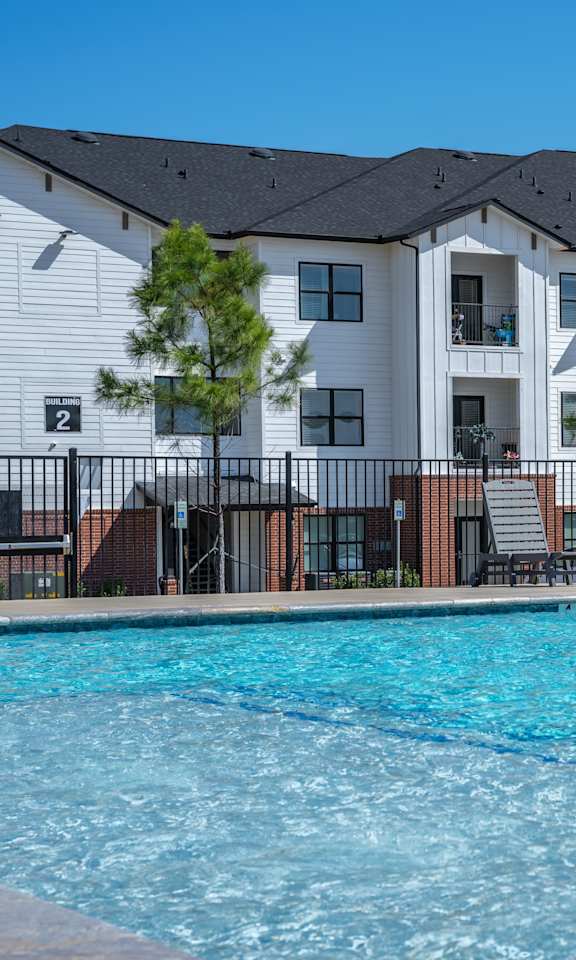 A large swimming pool in front of apartment buildings.