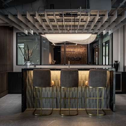 A bar with two stools and a gold and grey backrest.