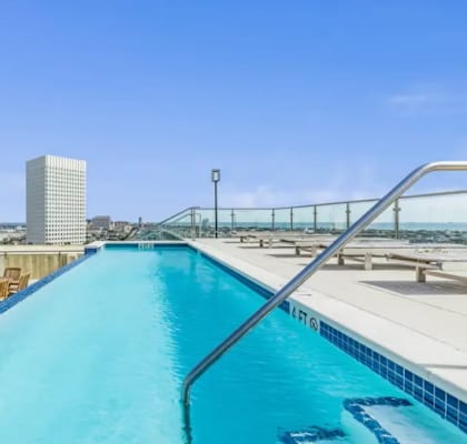 A swimming pool on a rooftop with a glass railing.