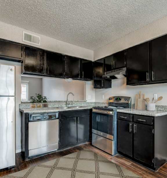 A kitchen with black cabinets and a stainless steel refrigerator.