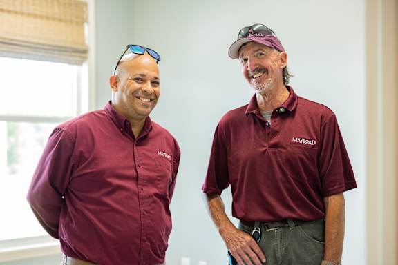 Two men wearing maroon shirts with the logo "MARATHON" on the chest are standing in a room.