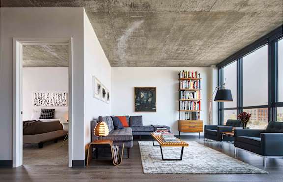 A living room with a grey couch and a wooden entertainment unit.