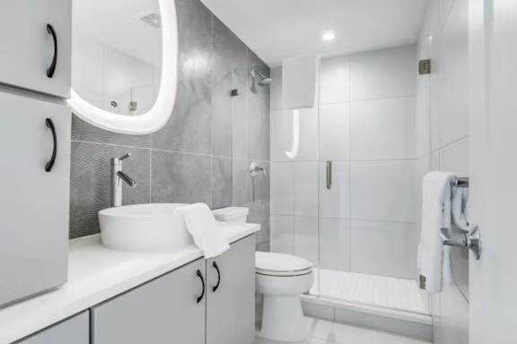A white bathroom with a sink, toilet, and shower.