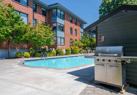 A barbecue grill is placed next to a small pool in a courtyard.