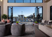Thumbnail 12 of 52 - A modern living room with grey couches and a large window overlooking a street at Solhavn Apartments, Utah