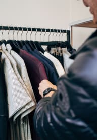 Man Looking Through Clothes on Clothing Rack