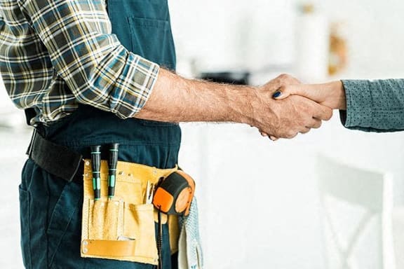 a man shaking hands with a technician with a tool belt