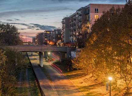 A bridge over a road with trees on the side and a building in the background.