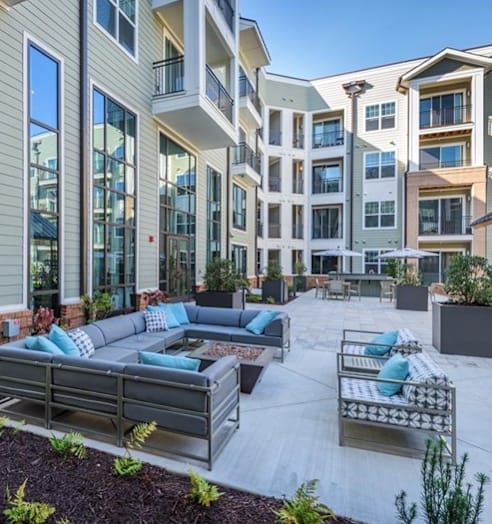 an outdoor living area with couches and chairs in front of an apartment building