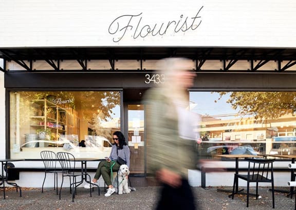 a woman sitting outside a restaurant with her dog