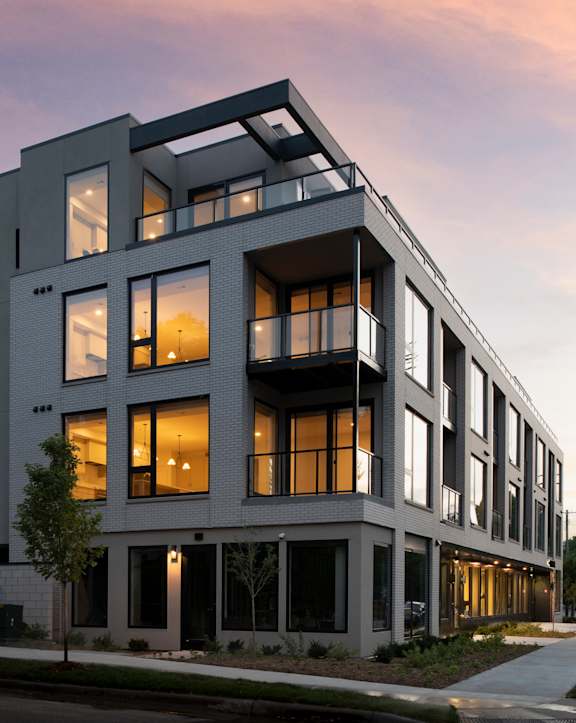 A modern apartment building with a mix of balconies and large windows.