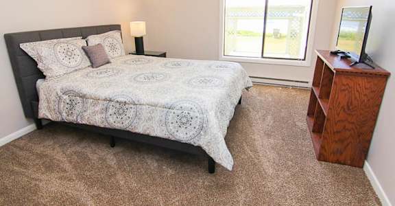 A bedroom with a bed, nightstand, and window.