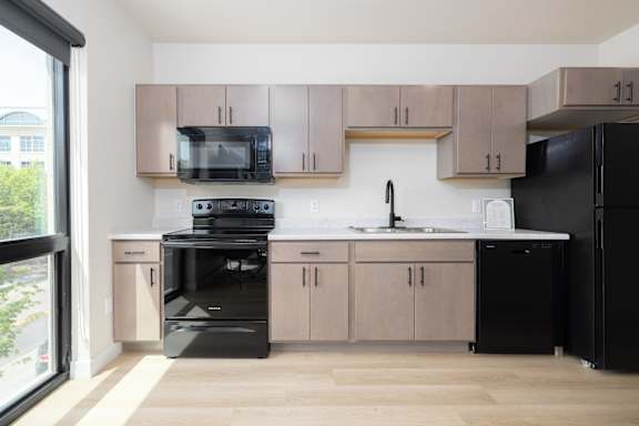 A kitchen with black appliances and wooden cabinets.
