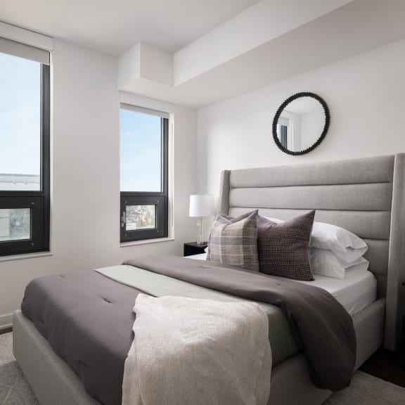 a bedroom with a large bed and two windows