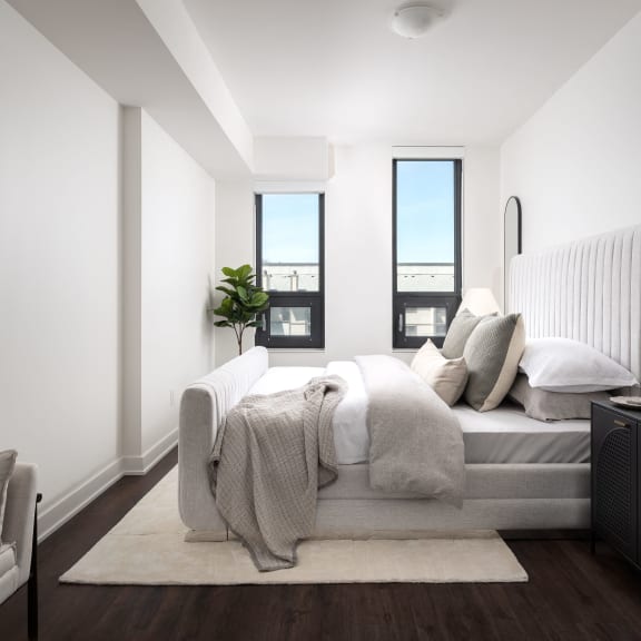 a bedroom with white walls and a bed with pillows and blankets