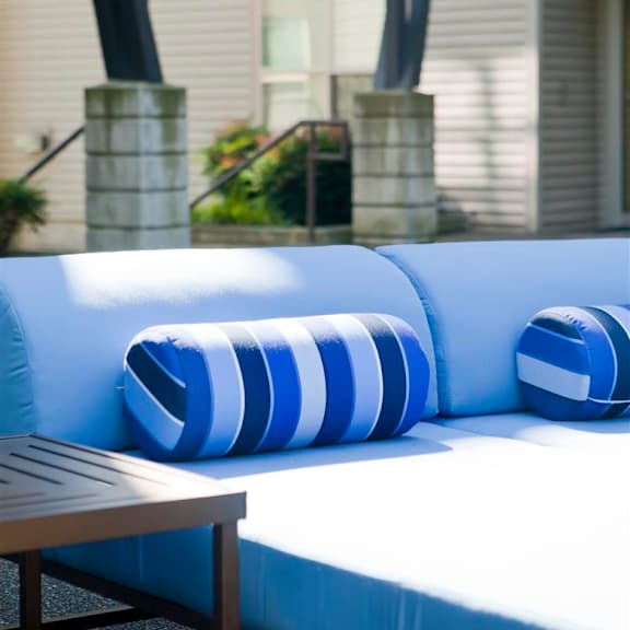 A blue and white striped cushion on a white couch.
