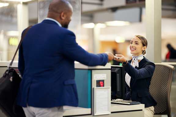 A man in a blue jacket is handing a card to a woman in a black blazer.