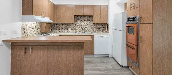 A kitchen with wooden cabinets and a white dishwasher at The Phoenix Apartments on 6th Avenue, Phoenix