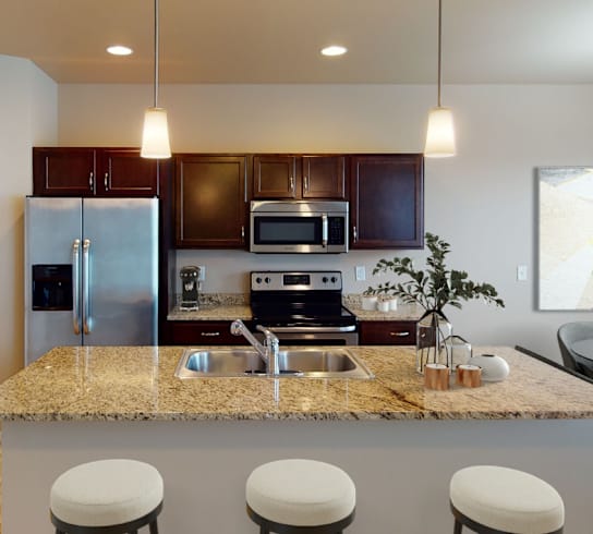 A kitchen with a granite countertop and bar stools.