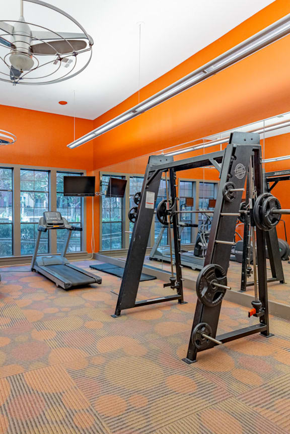 A gym with orange walls and a variety of exercise equipment.