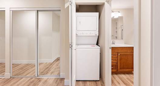 A white refrigerator is in a room with a wooden floor.