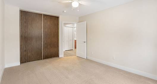A room with a ceiling fan and a door leading to another room.
