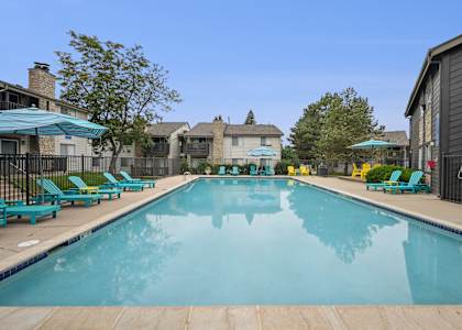 A large swimming pool with blue lounge chairs and umbrellas.