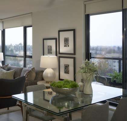 A modern living room with a glass table and a view of the city.