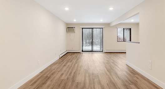 A room with wooden flooring and a sliding glass door.