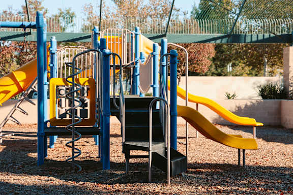 A playground with a yellow slide and a black slide.