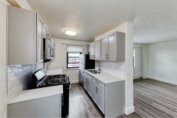 A kitchen with white cabinets and a black stove top oven.