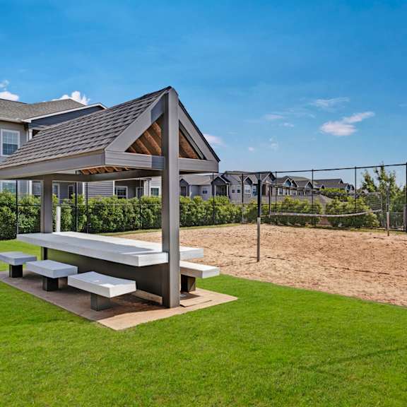 A picnic area with a picnic table and benches next to a volleyball court at Lincoln at Central Park.