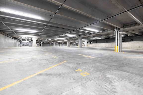 A spacious parking garage with concrete floors and yellow lines.