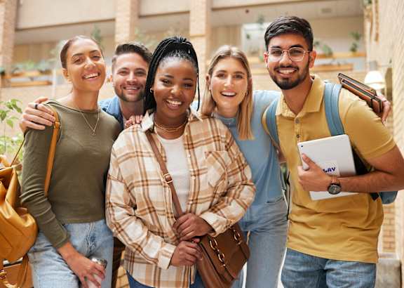 A group of five people stand close together, smiling and posing for a photo.