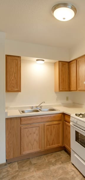 A kitchen with wooden cabinets and a white stove top oven. at Northeast Villas, Fridley, 55421