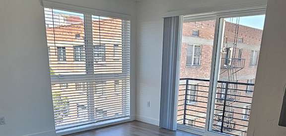 A room with a ceiling fan and sliding glass doors.